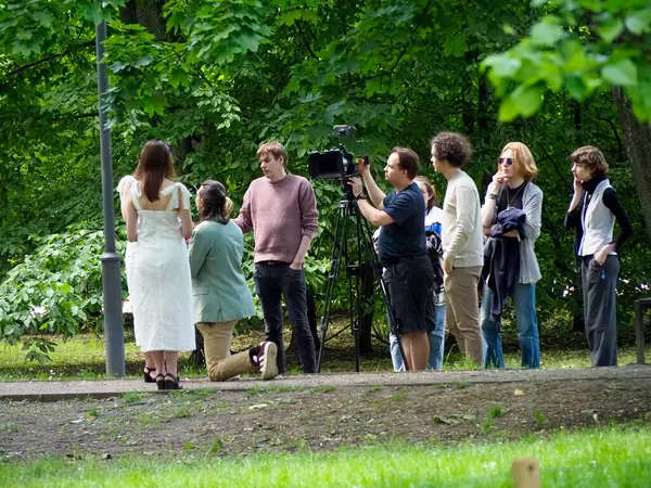 Bir grup zarif giyimli düğün davetlisi kutlama sırasında dışarıda yeşil park ortamında toplanıyor.