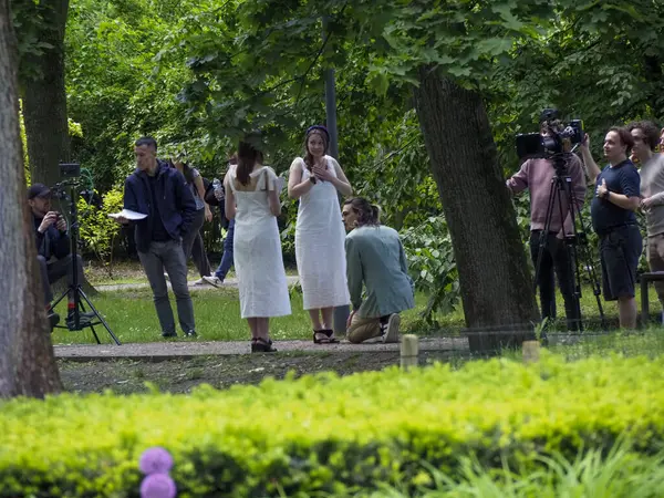 Gelin ve misafirlerin dışarıda toplandığı yemyeşil parkta düğün kutlaması.