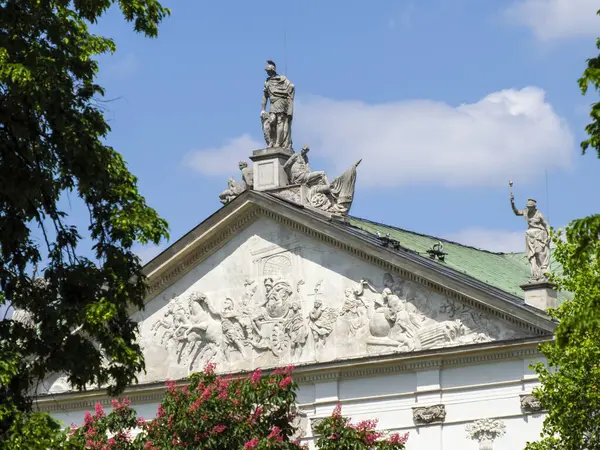 Mavi gökyüzünün altındaki yemyeşil kubbeli tarihi neoklasik bina.