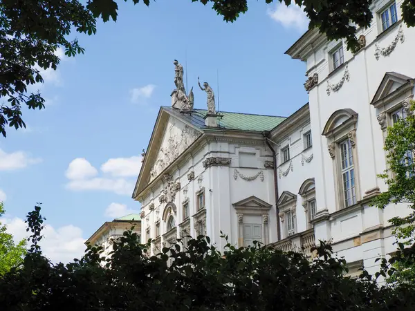 Mavi gökyüzü ve yeşil ağaçlara karşı dekoratif mimari detaylarla tarihi barok saray cephesi