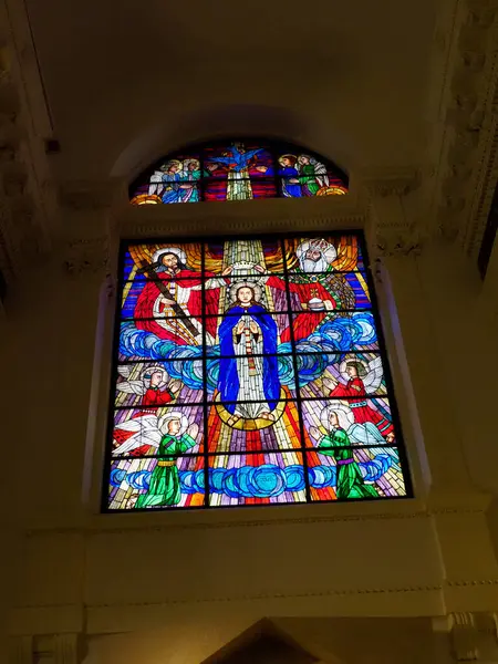 Canlı vitray pencereler, gotik mimari yoluyla yumuşak ışığı filtreleyen parlak renklerle karışık dini sahneler sergiliyor.