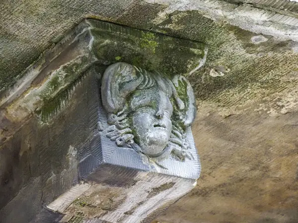 Yıpranmış mimari yapı elementinin üzerine antik taştan tuhaf bir yüz oyması.