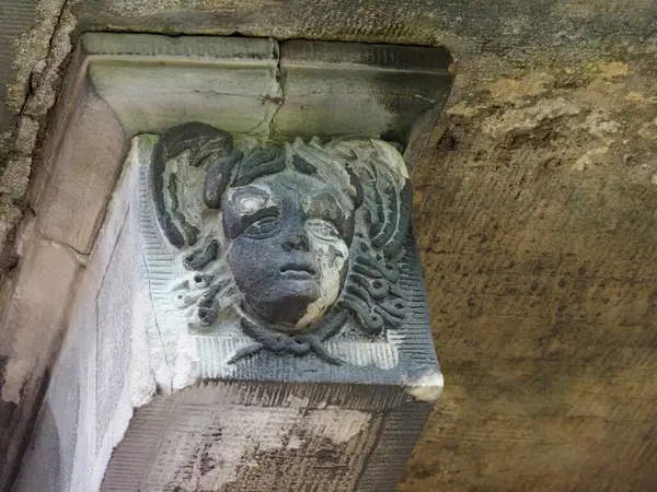Tarihi bina üzerine oyulmuş yüz detaylarıyla yıpranmış taş mimari korbel.