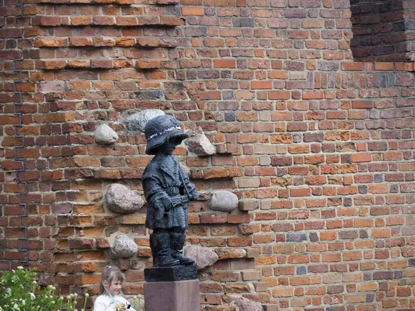 Ortaçağ şövalye heykeli tarihi tuğla kale arka planında nöbet tutuyor.