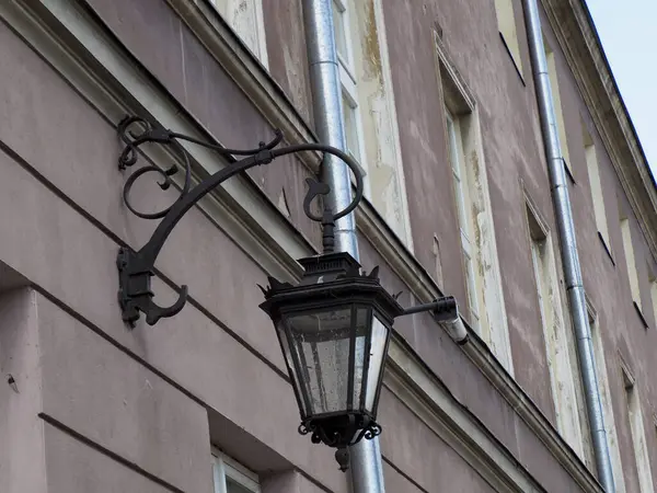 Geleneksel süslemeli sokak feneri tarihi binanın ön cephesine monte edilmiş. Eski şehirde atmosferik mimari ayrıntı yaratıyor.