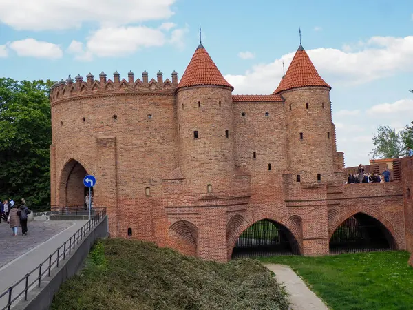 Ortaçağ Barbika giriş kapısı. Turistler tarihi kırmızı tuğla kemer köprüsünden geçiyorlar.