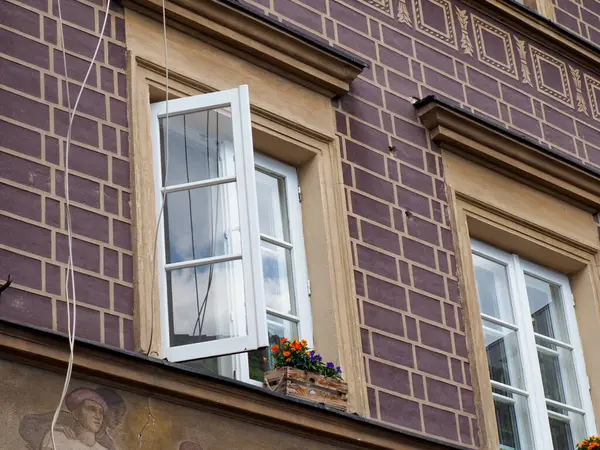 Beyaz çerçeveli pencereleri ve dekoratif çiçek kutularıyla geleneksel mimarinin yer aldığı tarihi Avrupa binası cephesi