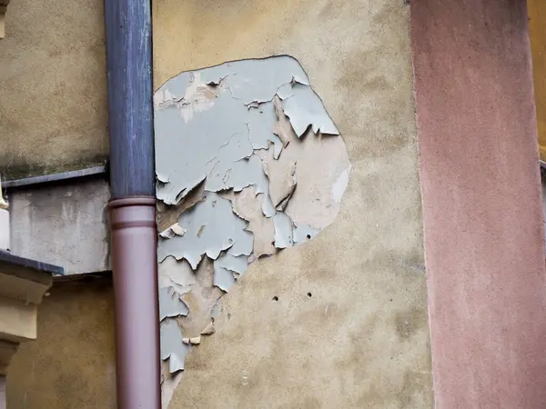 Yıpranmış bina duvarı, yüzey dokusunun bozulduğunu mimari tarihin katmanlarını ortaya çıkardığını gösteriyor.