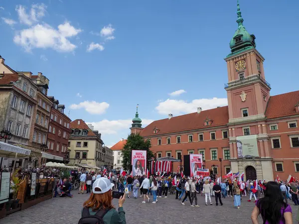 Turistlerin ve yerlilerin güneşli öğleden sonra kaynaştığı Varşova Kalesi Meydanı sahnesi