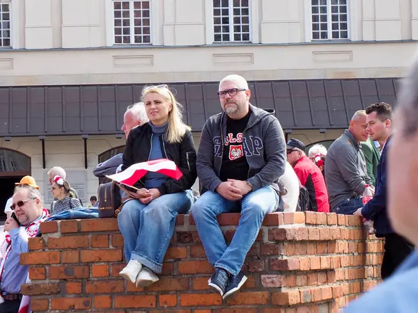 Tuğla duvarda oturan genç çift, şehir merkezinde Polonya bayraklarıyla vatanseverlik gösterisi yapıyorlar.