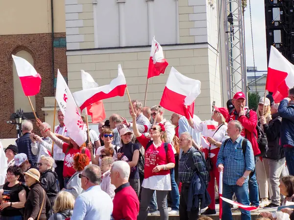 Polonya vatandaşlarının modern mimarinin önünde kırmızı ve beyaz bayraklar taşıdığı vatanseverlik gösterisi