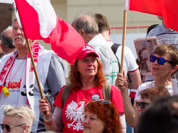 Polonyalı vatanseverler açık hava halk gösterileri sırasında ulusal bayraklar sergiliyorlar.
