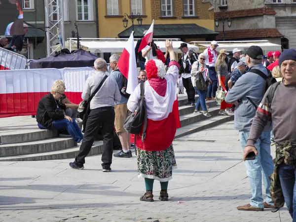 Geleneksel Polonya halk kostümlü yaşlı kadın Bağımsızlık Günü kutlamalarına kırmızı ve beyaz bayraklarla katılıyor