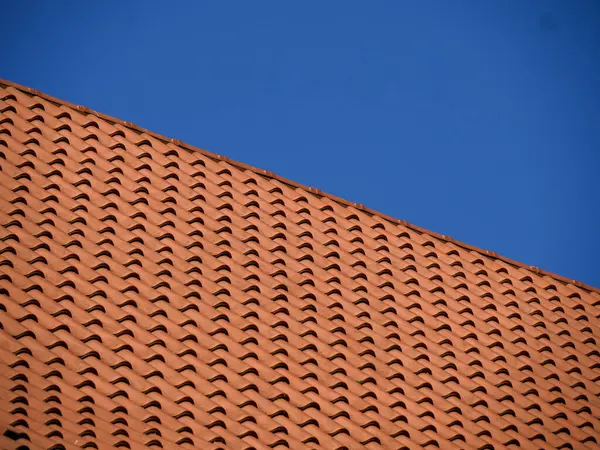 Kırmızı kil çatı kiremitlerinin tekrarlanan deseni geometrik doku ve mimari detay oluşturur