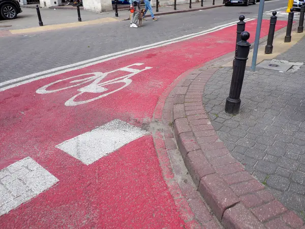 Beyaz oklarla kırmızı boyalı bisiklet yolu ve sokak kaldırımlarında uyarı sembolleri