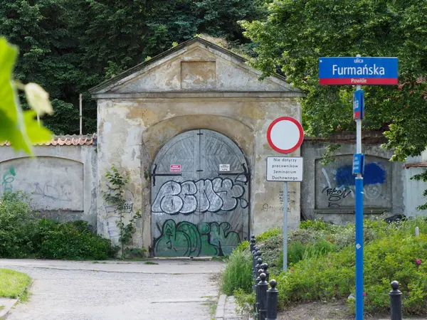 Grafiti kaplı tarihi taş kemer girişi yemyeşil bitki örtüsüyle çevrili.