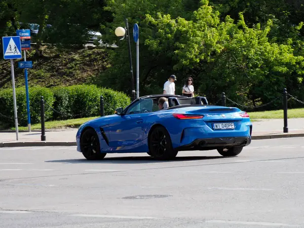 Lüks mavi spor araba trafik işaretleri ve yemyeşil yeşilliklerle şehir caddesinde konumlanmış.