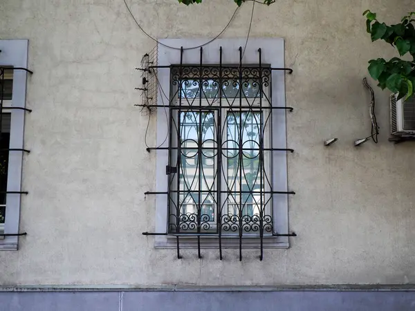 Geleneksel mimari tarzında dekoratif siyah metal parmaklıklı beyaz bina penceresi