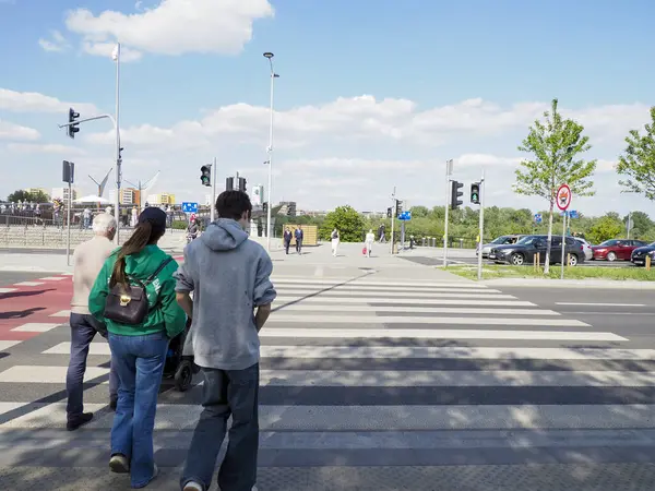 Varşova şehir merkezinde güneşli bir bahar gününde yaya geçidinde yürüyen iki kişi.