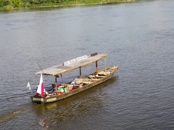 Geleneksel Polonya ahşap teknesi kırmızı ve beyaz bayraklı Varşova seti yakınlarındaki Vistula nehrinde huzur içinde yüzüyor.