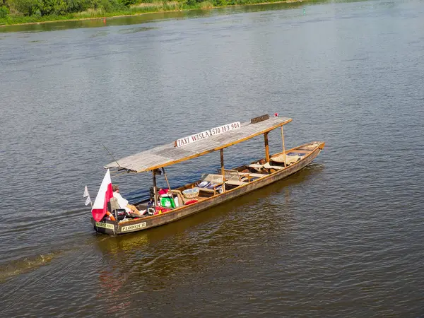 Polonya bayrağı taşıyan tahta gezici gemi Varşova yakınlarındaki Vistula nehri sularında yeşil kıyı şeridi boyunca ilerliyor.