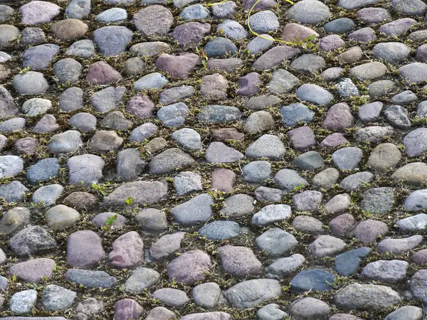 Yıpranmış doğal taş kaldırımın çeşitli renkli taşlarla yakın çekim dokusu.