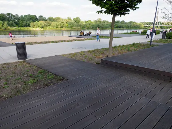 Güneşli bir günde huzurlu nehir marinasına giden ahşap geçitli modern rıhtım güvertesi.