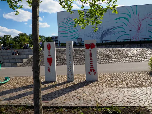 Çağdaş nehir kenarındaki banklar ve ağaçlarla akan suyun yanında huzurlu şehir inzivası sunuluyor.