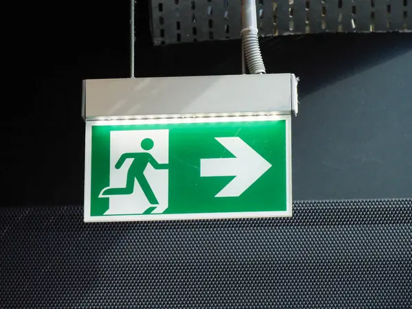 Endüstriyel tavandan sarkan koşan kişi simgesi ile yeşil acil çıkış işareti