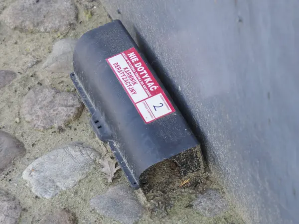 Kentsel çevrede beton zemin üzerine tehlikeli uyarı etiketleri yerleştirilmiş endüstriyel atık konteynırı