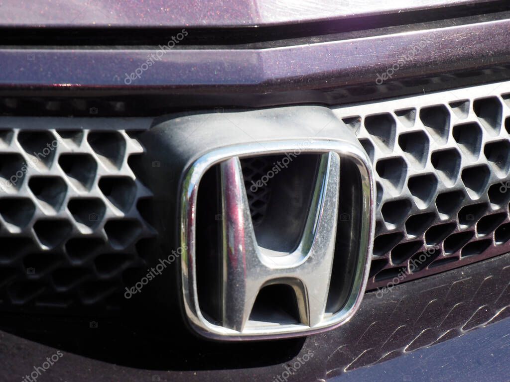 Honda logo emblem prominently displayed on black honeycomb grille pattern of modern vehicle