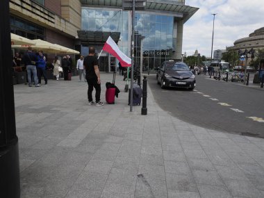 İnsanlar, Vatanseverlik kutlamaları sırasında işlek şehir caddesinde Polonya bayrak satıcısının önünden geçiyorlar.