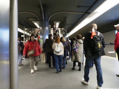 Renkli giysiler içinde seyahat zamanının zirvesinde modern metro istasyonunda yürüyen insanlar.