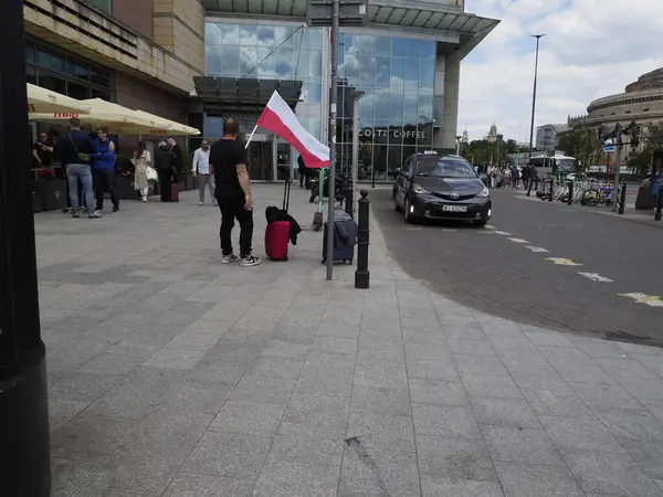 İnsanlar, Vatanseverlik kutlamaları sırasında işlek şehir caddesinde Polonya bayrak satıcısının önünden geçiyorlar.
