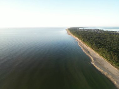 Zümrüt ormanının mavi sularla buluştuğu ve doğal körfezi oluşturan eğimli kıyı şeridinin dramatik hava perspektifi