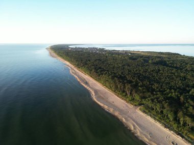 Yoğun yeşil ormanlarla çevrili el değmemiş kumlu sahil yarımadasının hava manzarası sakin mavi sularla buluşuyor.