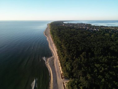 Sık orman ve kumlu kumlu gök mavisi sular arasında yuva yapmış kıyı yerleşiminin nefes kesici manzarası.