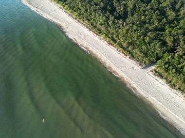 Turkuaz suları olan el değmemiş kıyı şeridi havadan kumlu sahille buluşuyor.