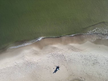 Tek başına sahile giden kişinin, el değmemiş kıyı çöllerine karşı çarpıcı bir insan unsuru yarattığının havadan görüntüsü.