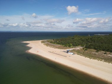 Baltık Denizi 'nin ormanlarla çevrili turkuaz sularına uzanan uzun kumlu sahil yarımadasının çarpıcı hava manzarası.