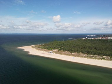 Turkuaz Baltık Denizi sularıyla çevrili kıvrımlı kumlu sahil yarımadasının havadan görünüşü.