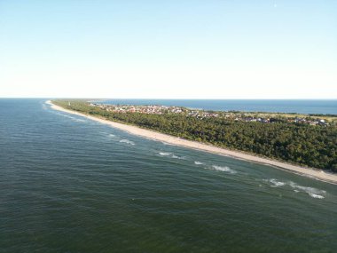 Baltık Denizi dalgalarının yeşil kıyı ormanlarına çarpan dramatik hava perspektifi