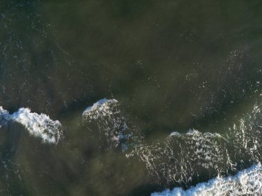 Beyaz köpük ve karanlık sularla çevrili Baltık Denizi kayalarının dramatik hava görüntüleri.