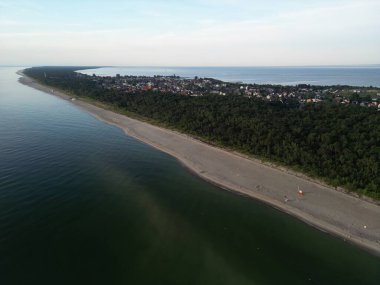 Karanlık suları ve denize uzanan orman yarımadası ile kıvrımlı kıyı şeridinin dramatik hava perspektifi