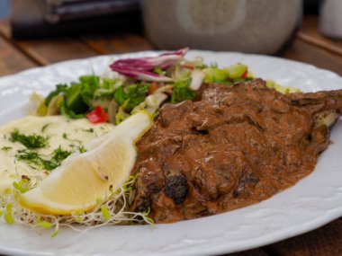 Lezzetli ızgara biftek, kremalı patates püresi ve canlı salata karışımı. Beyaz restoran tabağında çok güzel sunulmuş.