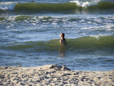 Genç insan, köpüklü beyaz dalgalarla turkuaz okyanus sularında ferahlatıcı yüzmenin keyfini çıkarıyor.