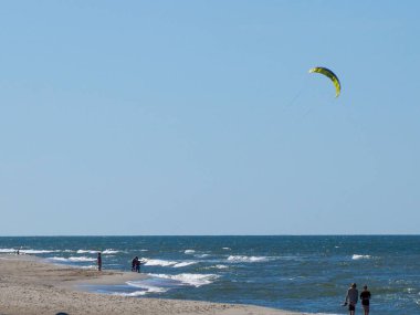 Sahile yakın okyanus dalgaları üzerinde uçan sarı uçurtmalı uçurtma.