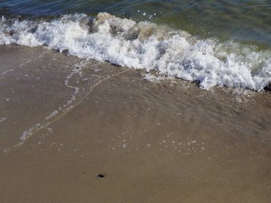 Deniz köpüğünün ve kabarcıkların yakından görüntüsü ıslak kumlu kıyılarda eriyip gidiyor.
