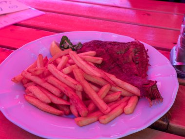 Renkli açık hava yemek yüzeyinde servis edilen kırmızı sebze çubuklarıyla dolu pembe tabak.