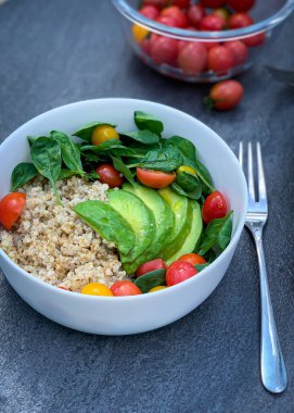 Bir tabak pirinç, erik domates, avokado ve çatalla servis edilen ıspanak. Lezzetli ve besleyici bir yemek. Zımba ve yapraklı sebzelerin karışımı.